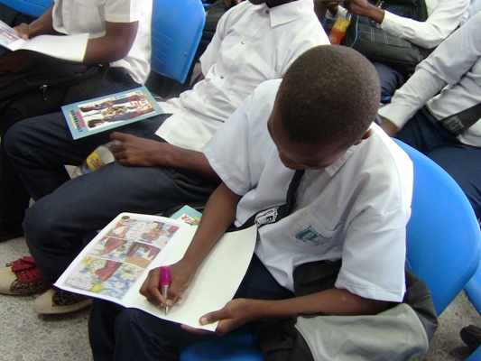 Israël Masanka dédicaçant des exemplaires de sa BD Israël Masanka dédicaçant des exemplaires de sa BD