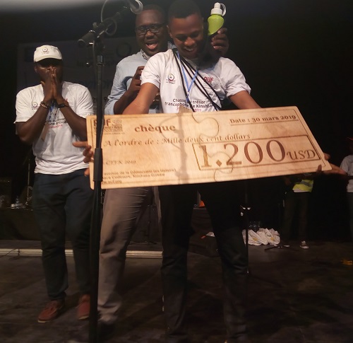 Le Cartel jubilant avec son chèque sur le podium de l’Institut français, Halle de la Gombe 